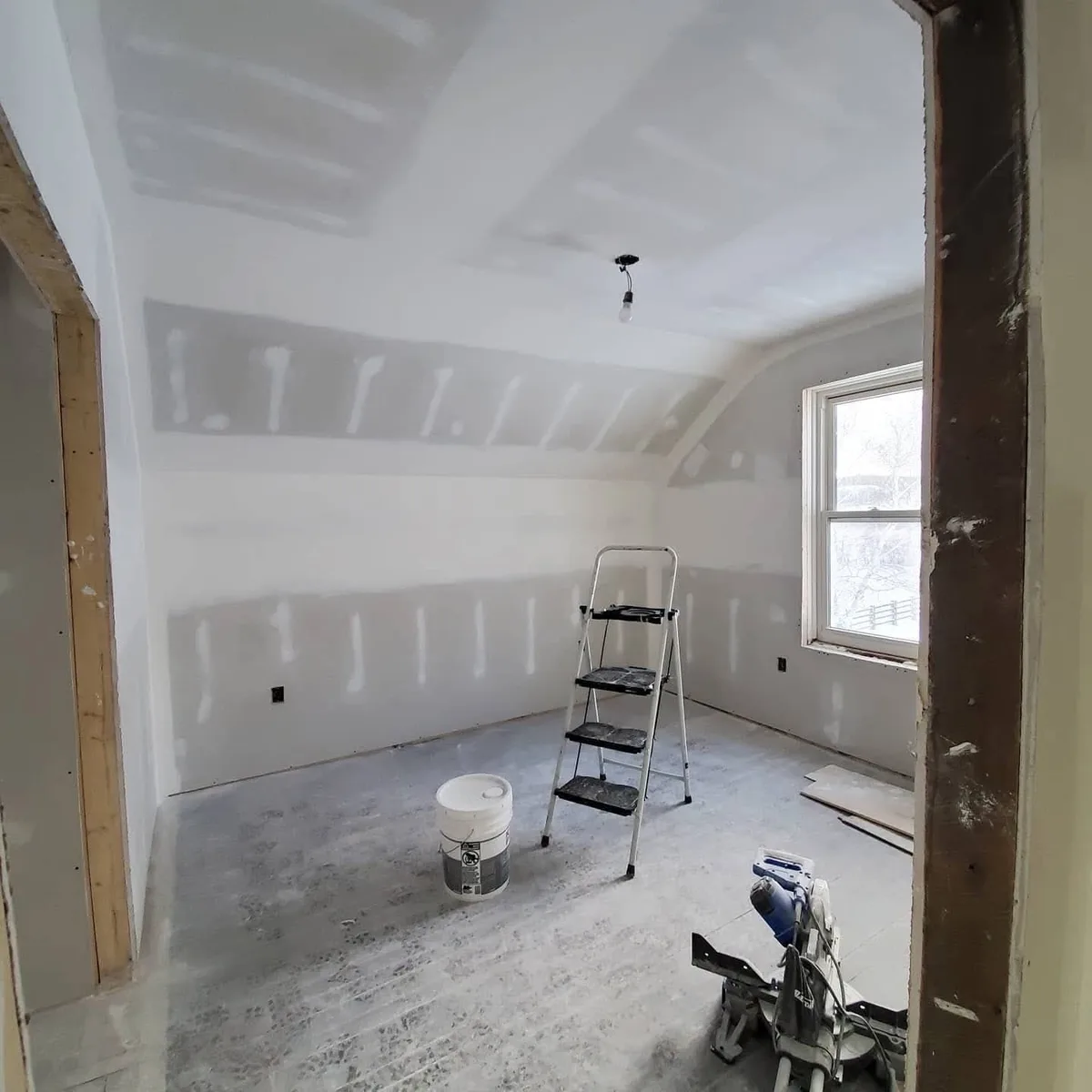 Taped walls and a sloped ceiling transition in a smaller room.