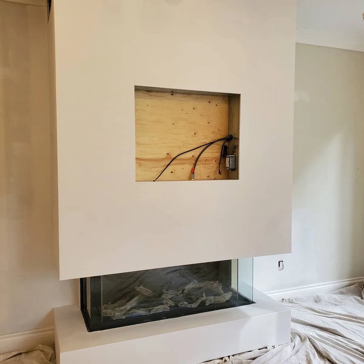Smooth drywall planes around a three-sided fireplace and recessed media opening.