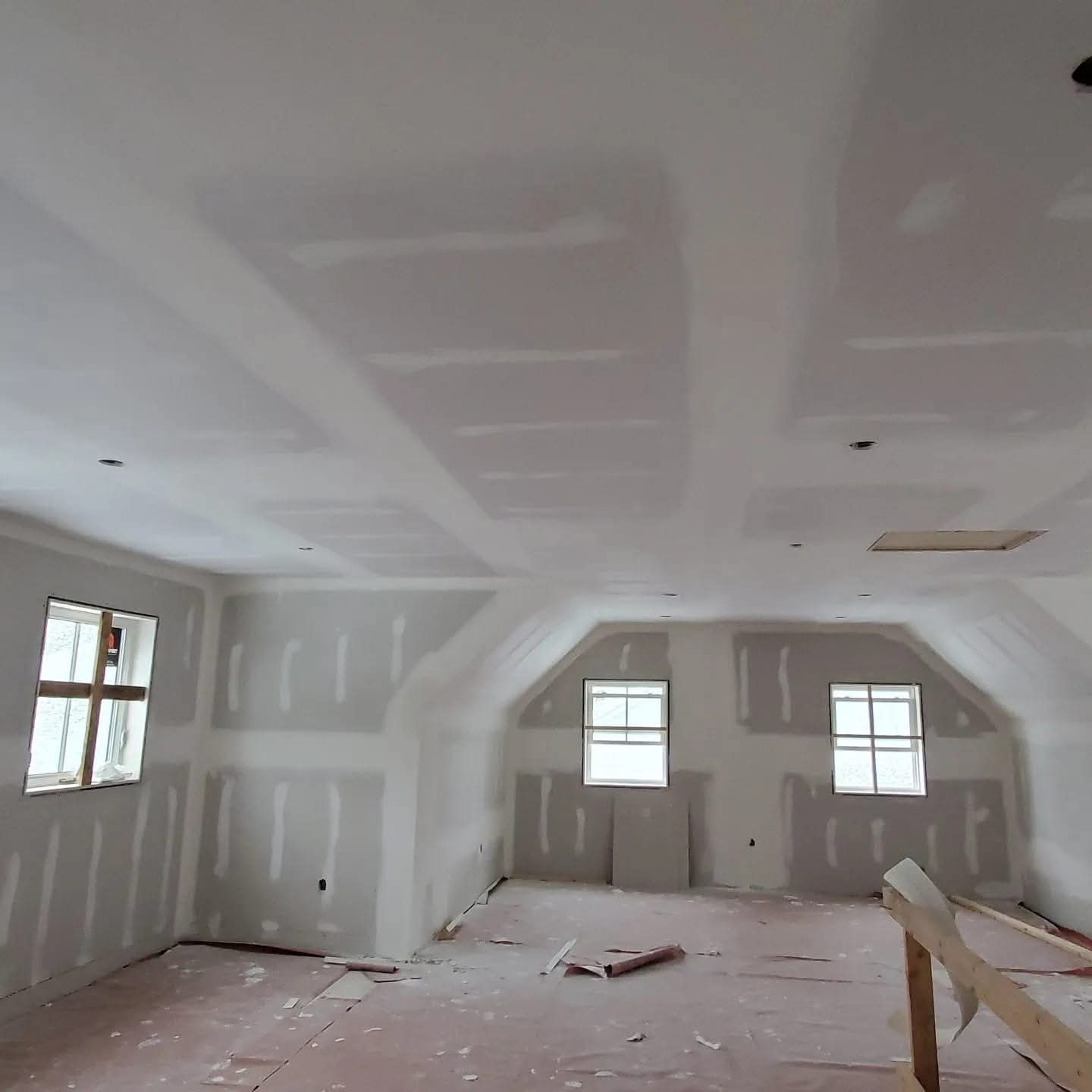 Large attic bonus room with sloped ceilings and taped drywall ready for final finishing