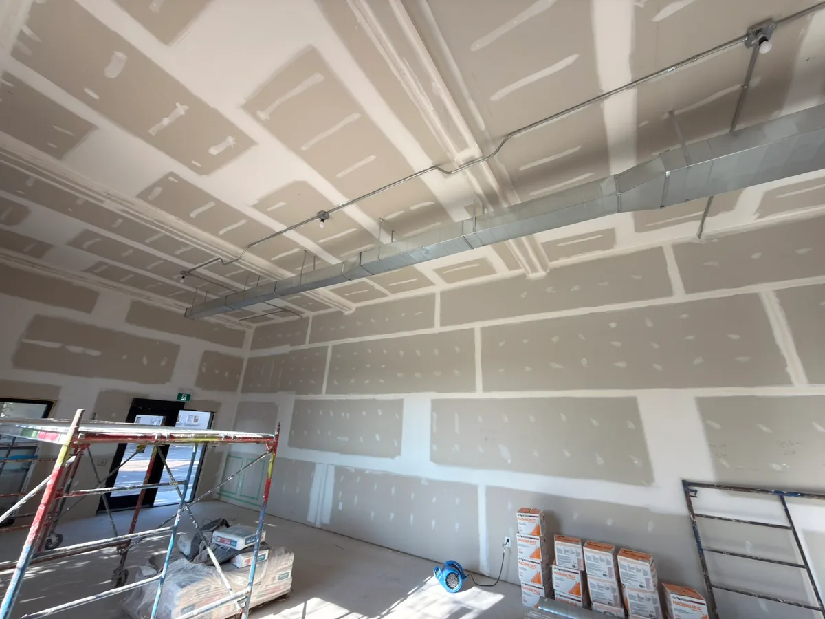 Tall taped walls and ceiling details alongside exposed ductwork and conduit.