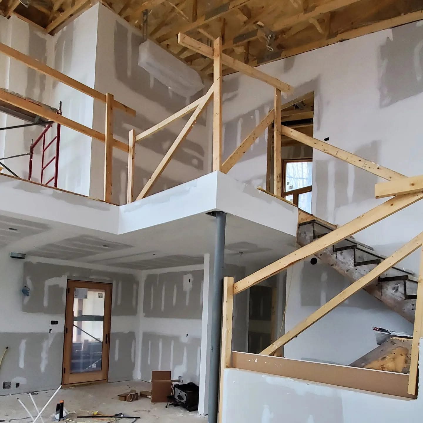 Large multi-level new-build interior with drywall installed and taped around the stair and loft areas