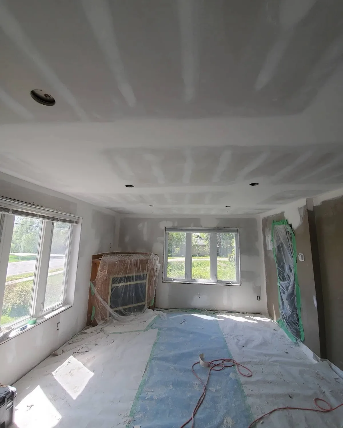Wall and ceiling finishing with the floor and existing fireplace covered.