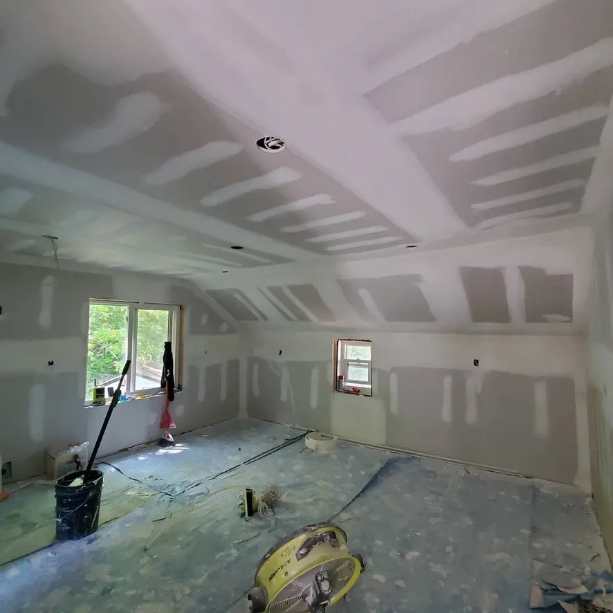 Wall and ceiling seams in a room with sloped upper walls and covered floors.