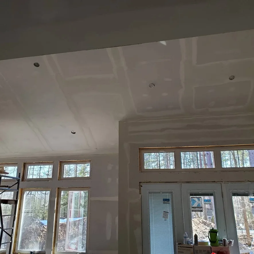Taped ceiling and wall transitions above tall windows and glazed doors.